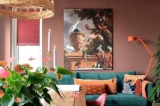 a beautiful muted-colored living room with chocolate brown walls, a green sofa with orange pillows and a lamp, an artwork and a dining zone