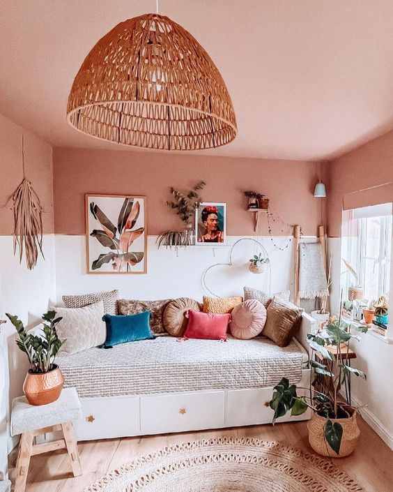 a boho space with a pink ceiling, a daybed with pillows, a gallery wall, potted plants and a jute rug plus some decor