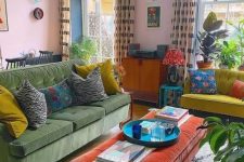 a bold eclectic living room with pink walls, a green sofa, a neon yellow loveseat, an orange ottoman, potted plants and bright artwork