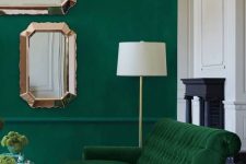 a bold living room with an emerald wall, a green velvet sofa and touches of gold and copper for more chic