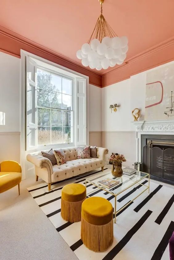 a bold living room with an orange ceiling, white walls and floor, a chic Chesterfield sofa, yellow furniture and a fireplace