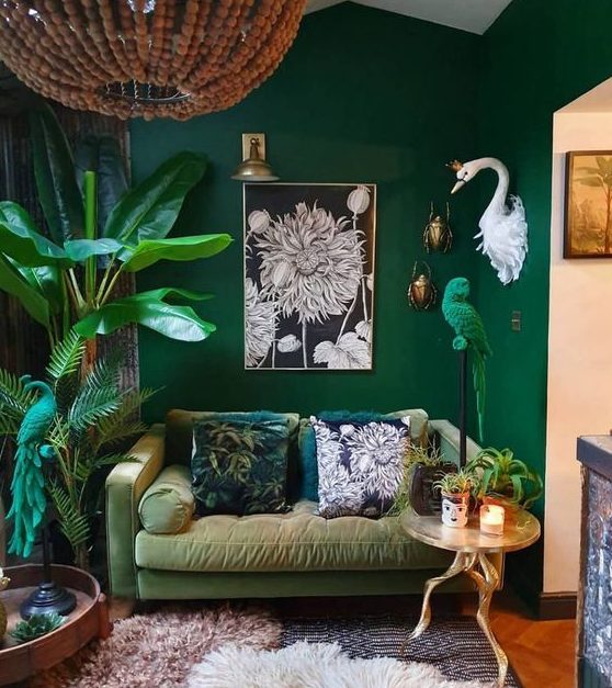 a bold living room with emerald walls, a muted green sofa, potted plants and a parrot figurine in emerald