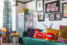 a bold maximalist living room with an orange ottoman, a green sofa, a gallery wall with bold art and colorful pillows