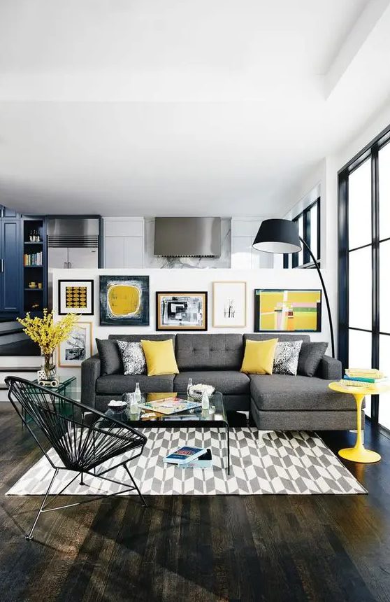 a bold modern living room with a grey sectional, a printed rug, a bright gallery wall, a black floor lamp and a yellow table
