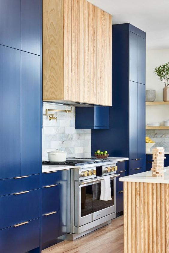 a bright blue kitchen with a stained fluted hood, a fluted kitchen island and white stone countertops