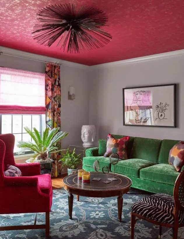 a catchy eclectic living room with a green sofa, a pink chair, curtain and a ceiling, a round table and a zebra print chair