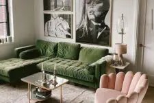 a chic living room with a green sectional, a pink curved chair, a coffee table, a gallery wall and a chandelier