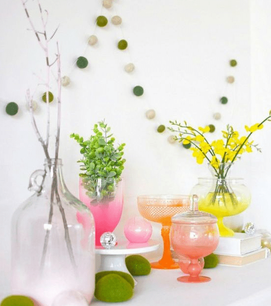 a colorful spring display with moss eggs, bright neon ombre vases and blooming branches and greenery