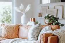 a comfy amber leather sofa styled with knit and crochet pillows and blankets is very cozy and inviting