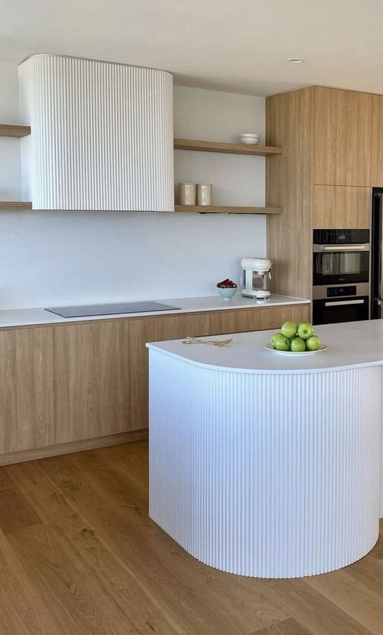 a contemporary kitchen with stained cabinets, open shelves, a white fluted hood and a curved kitchen island that matches