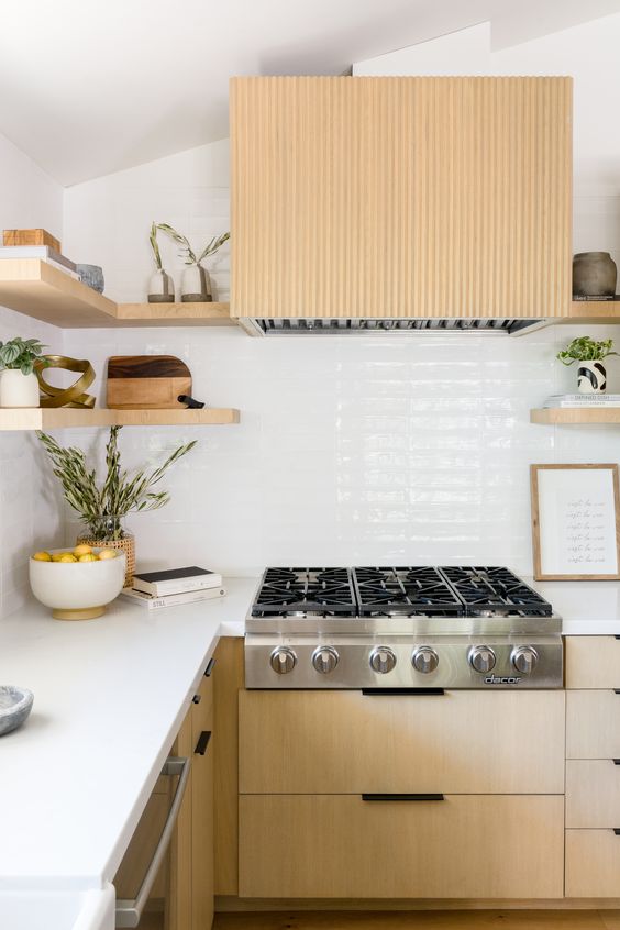a contemporary light-stained kitchen with a white backsplash and countertops, a fluted hood and open shelves