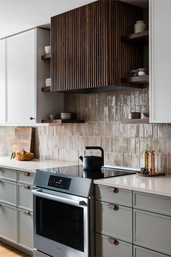 A cool grey modern kitchen with white countertops, a Zellige tile backsplash, a dark stained fluted hood and open shelves