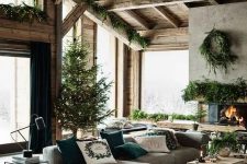 a cozy modern rustic living room with a fireplace, a grey sectional, a wooden coffee table and lots of evergreens for Christmas