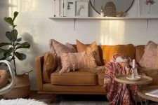 a cozy warm-colored boho living room with a tan sofa and pink pillows, hairpin leg tables, a printed rug, jute poufs and a woven pendant lamp