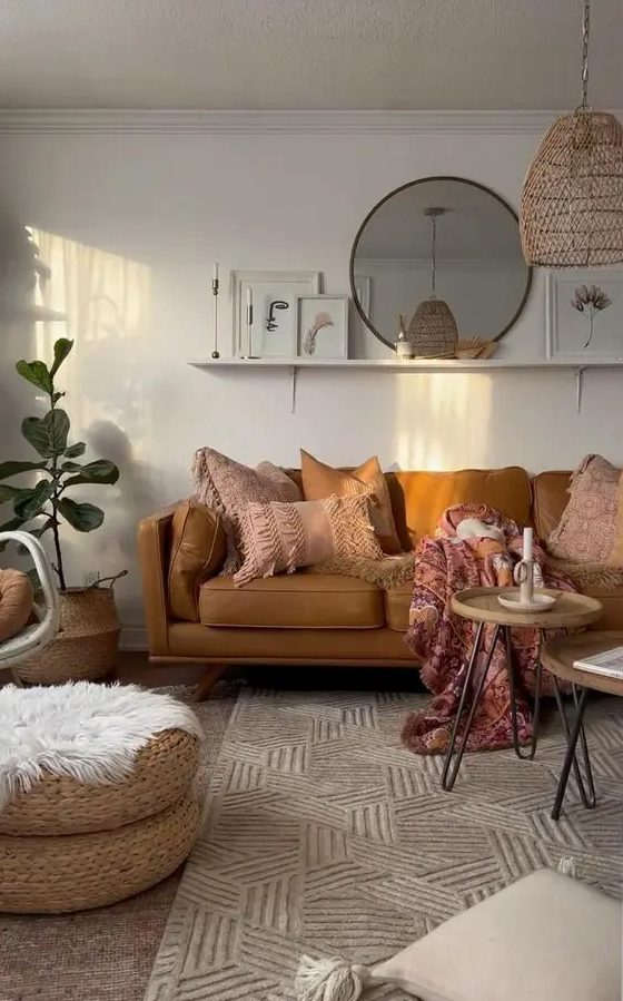 A cozy warm colored boho living room with a tan sofa and pink pillows, hairpin leg tables, a printed rug, jute poufs and a woven pendant lamp