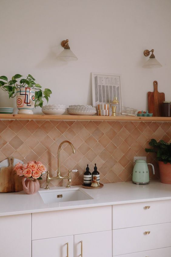 a creamy kitchen with white countertops, a diagonal terracotta tile backsplash and an open shelf fro storage and decor