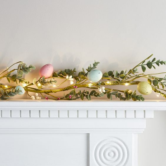 a creative Easter garland of a greenery branch, lights and pastel eggs, just remove them when Easter is over