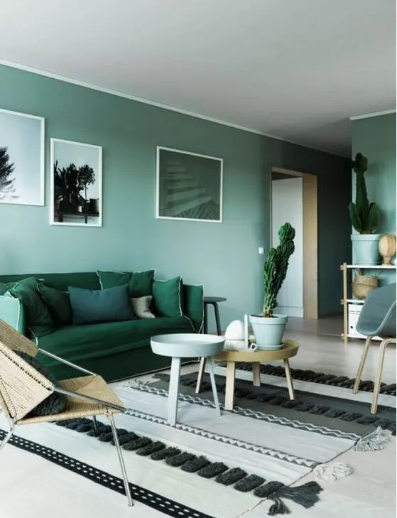 a green monochromatic living room with light green walls, an emerald sofa, green pots with cacti and artworks