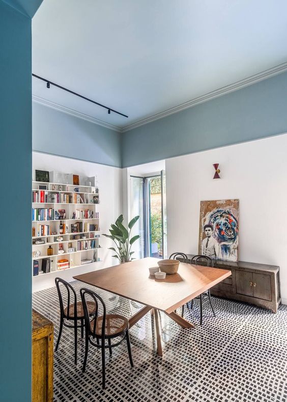 a home office or study room with open shelves, a blue ceiling, a desk, some chairs and a credenza with an artwork