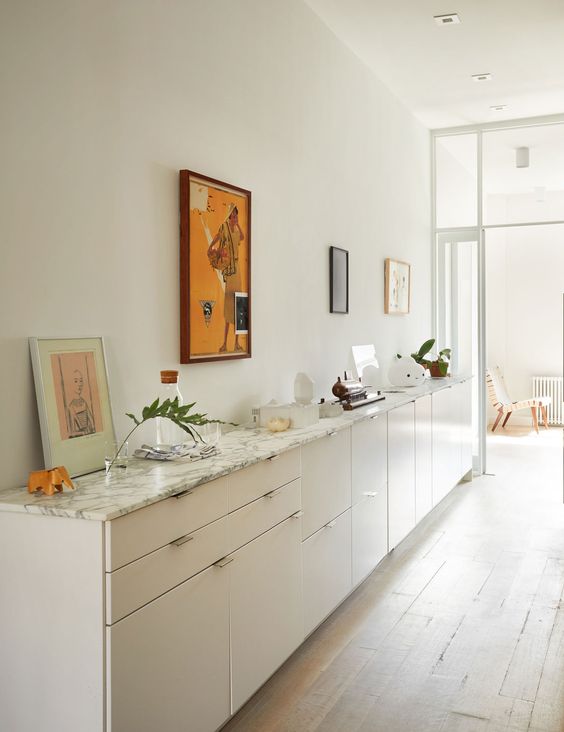 a large white console table with a marble countertop composed of IKEA Metod cabinets, with decor and artwork is adorable