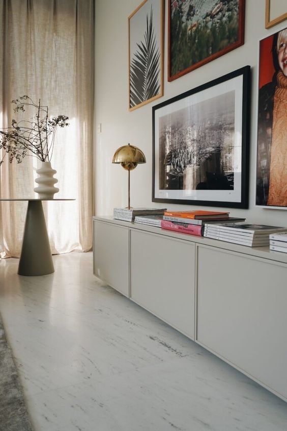a light grey sideboard of IKEA Metod units, with books and a gold table lamp plus a gallery wall