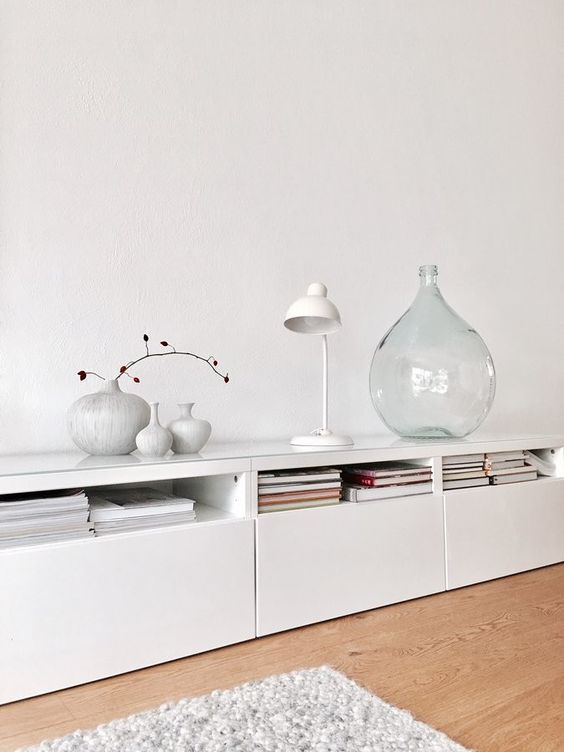 a long white sideboard of IKEA Metod units, with books, lamps and vases is ideal for a Scandinavian space