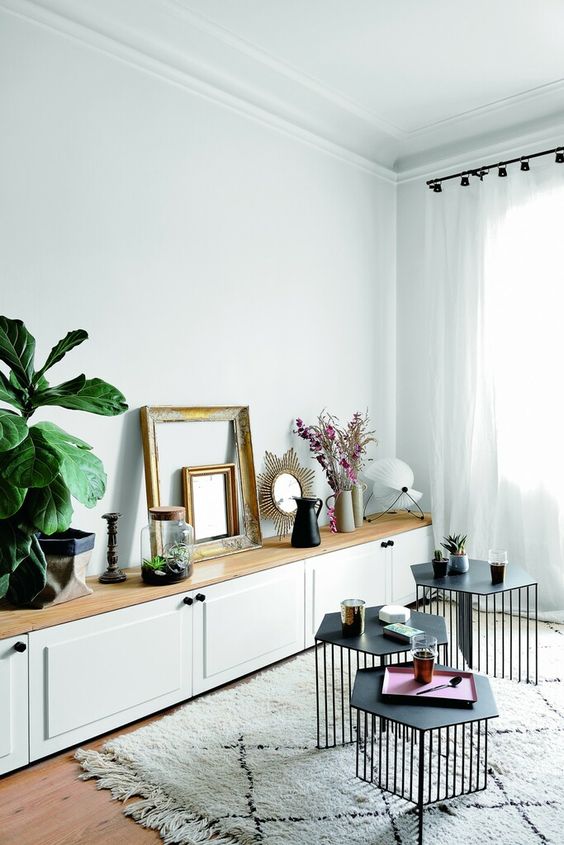 a long white storage unit of IKEA Metod with shaker doors, a wooden tabletop, greenery, grames and decor