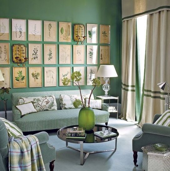 a lovely green living room with green walls, curtains and striped furniture, with a large vintage gallery wall