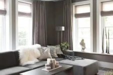 a lovely taupe contemporary living room with a matching low sofa, taupe curtains, a taupe coffee table with lots of candles and a taupe pendant lamp