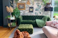 a maximalist living room with a faux stone wall, a green and a pink sofa, a green ottoman, a printed rug and potted plants is chic