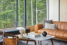 a mid-century modern livign room with a tan leather couch, a black daybed and chairs, a coffee table and printed chairs