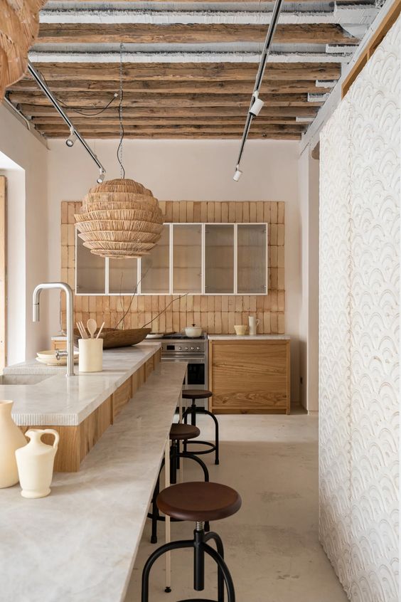 a modern country kitchen with stained cabinets, a terracotta tile backsplash, a large kitchen island with an eating zone