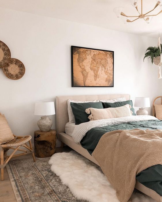 a modern earthy living room with a greige bed and earthy bedding, layered rugs, side tables and lamps and some boho decor