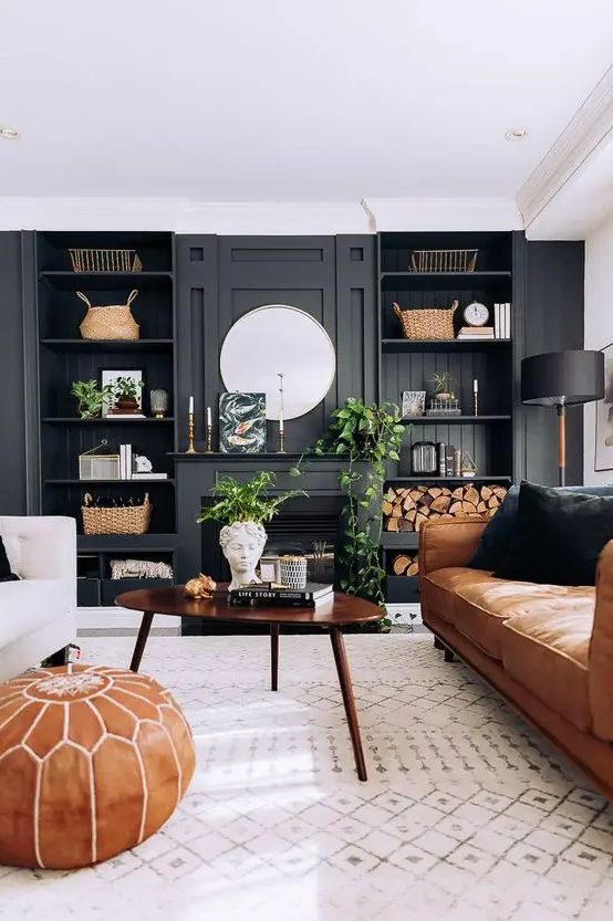 a modern farmhouse living room with a black accent wall and built-in shelves, a fireplace, an amber leather couch, a coffee table and a creamy sofa