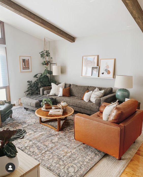 a modern farmhouse living room with layered rugs, a grey sofa, an amber chair, a gallery wall and a coffee table with greenery