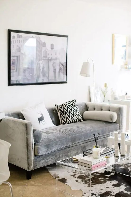 a modern living room is added a textural touch with an acrylic table and a grey velvet sofa