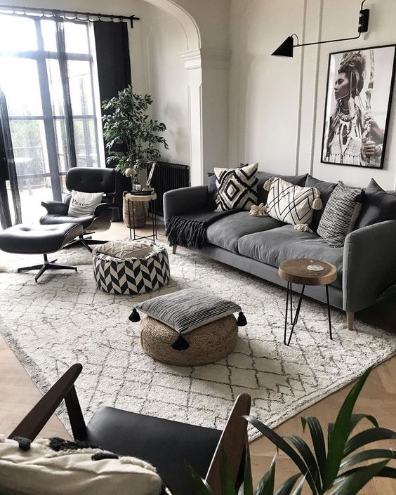 a modern meets boho living room with a grey sofa, black chairs, an artwork, a potted plant and some black touches