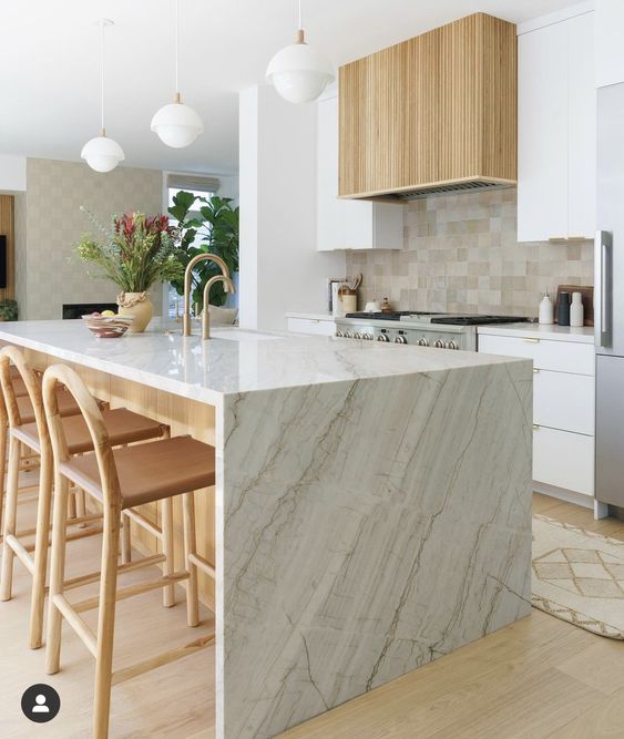 a modern neutral kitchen with white cabients, a fluted hood, a tan tile backsplash, a kitchen island with chic tall stools