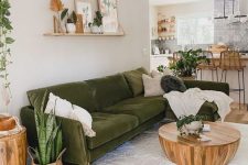 a modern neutral living room with a dark green sofa for an accent, potted plants, a coffee table and a shelf gallery wall