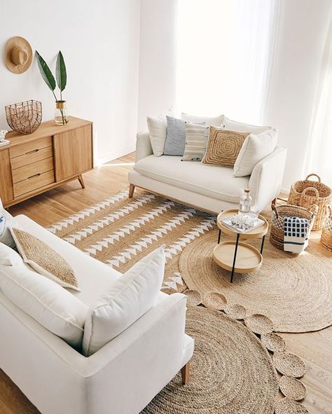 a neutral boho living room with creamy seating furniture, layered rugs, a stained credenza, baskets and tables