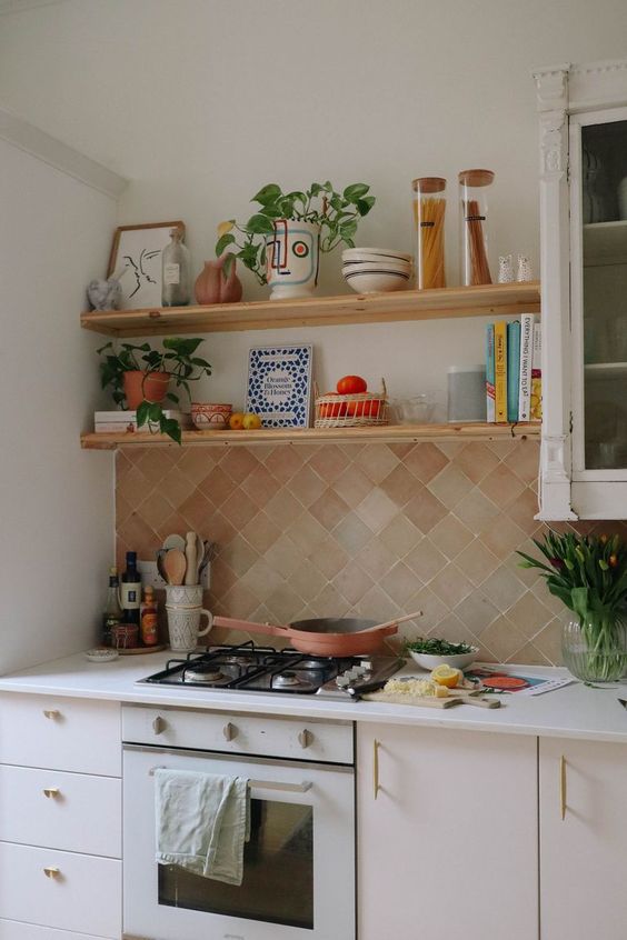 a neutral kitchen with a diagonal terracotta tile backsplash, open shelves, potted greenery and lovely decor