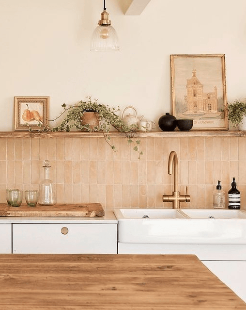 a neutral kitchen with white cabinets, a blush stacked tile backsplash, an open shelf and some decor