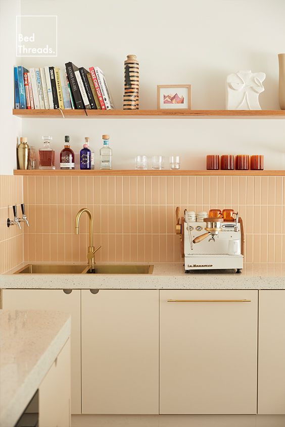 a neutral kitchen with white terrazzo countertops and a skinny terracotta tile backsplash, open shelves and some decor