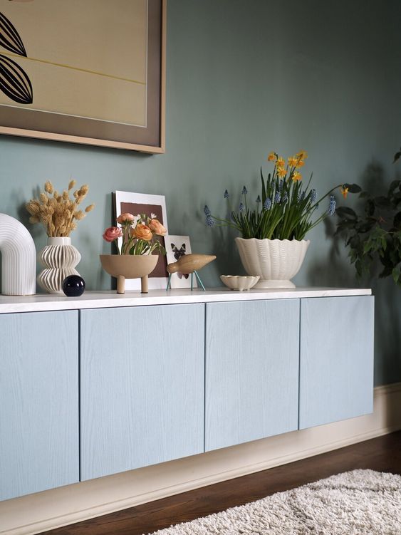 a pastel blue floating credenza of IKEA Metod units, white countertop, blooms, plants and chic decor