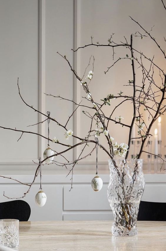 a refined centerpiece of blooming branches and neutral decorated eggs is a cool idea for a modern or Scandinavian space