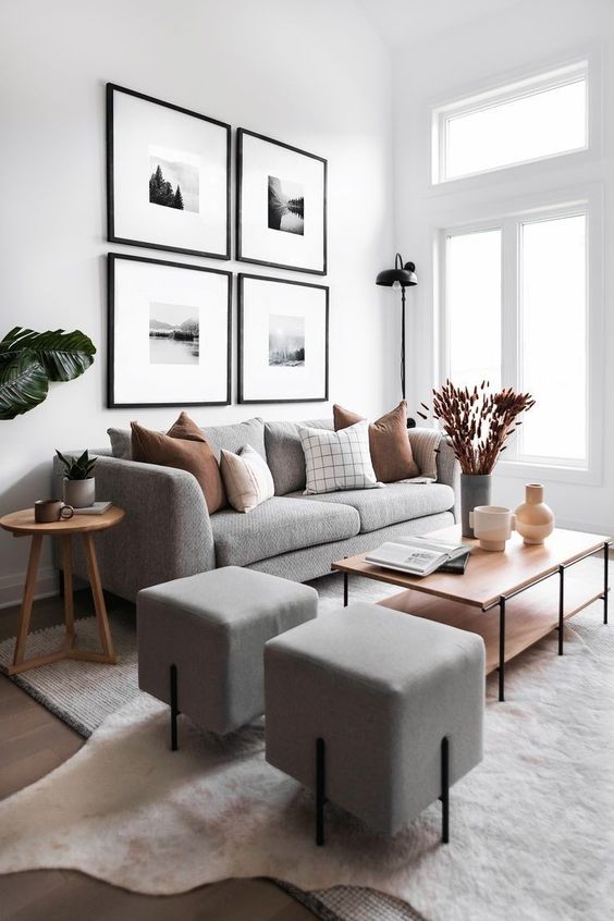 a serene Scandinavian living room with a light grey sofa and poufs, a coffee table, a side table, a gallery wall and some greenery