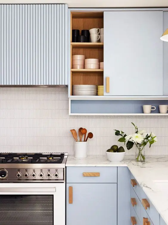 a serenity blue kitchen with a stacked tile backsplash, white stone countertops, wooden handles and some blooms