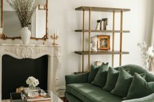 a sophisticated living room with a fireplace, a green sofa, a tiered coffee table, a shelving unit, a chandelier and a mirror