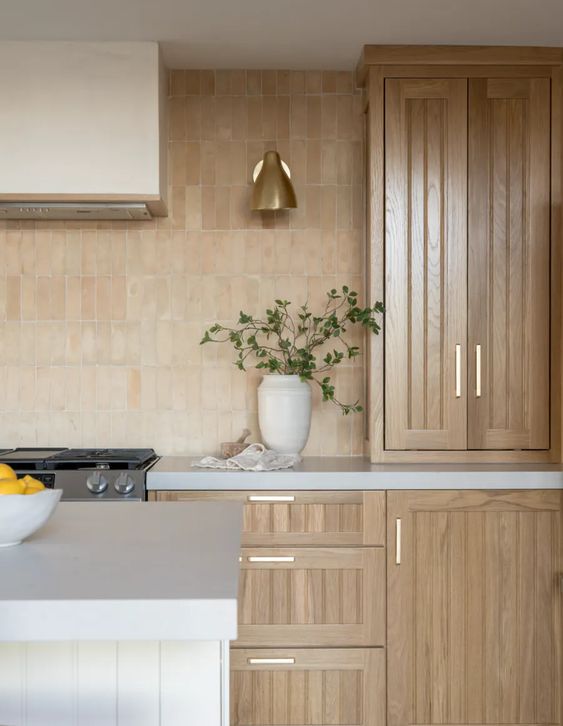 a stained fluted kitchen with white countertops and unglazed terracotta tiles, a white kitchen island and a gold lamp