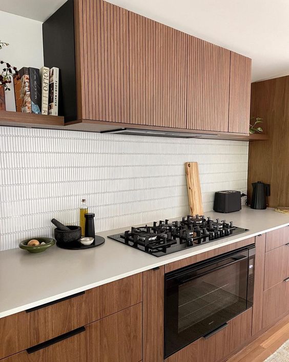 a stained modern kitchen with white countertops, a stacked tile backsplash, a fluted hood is a chic space